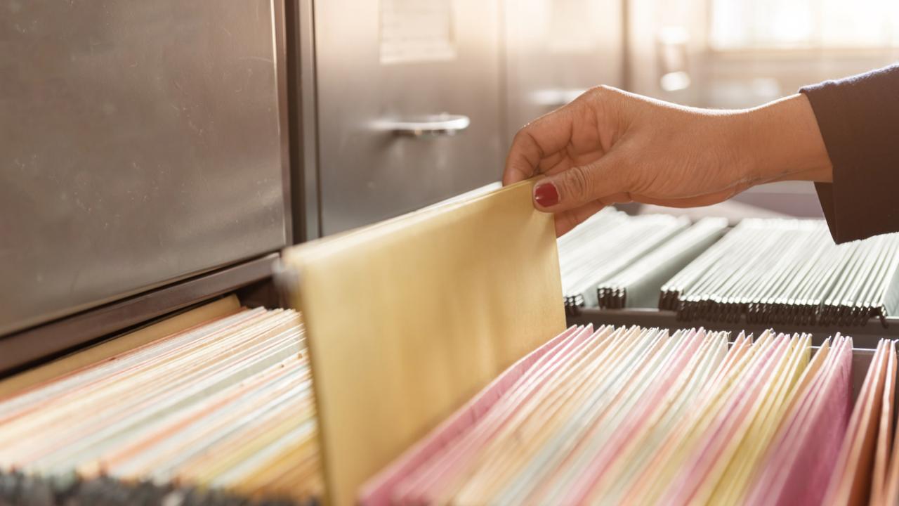 Image of a hand pulling a file from a drawer full of files. 