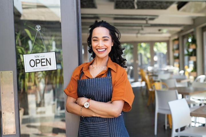 Image of a woman standing in front of her small business. 