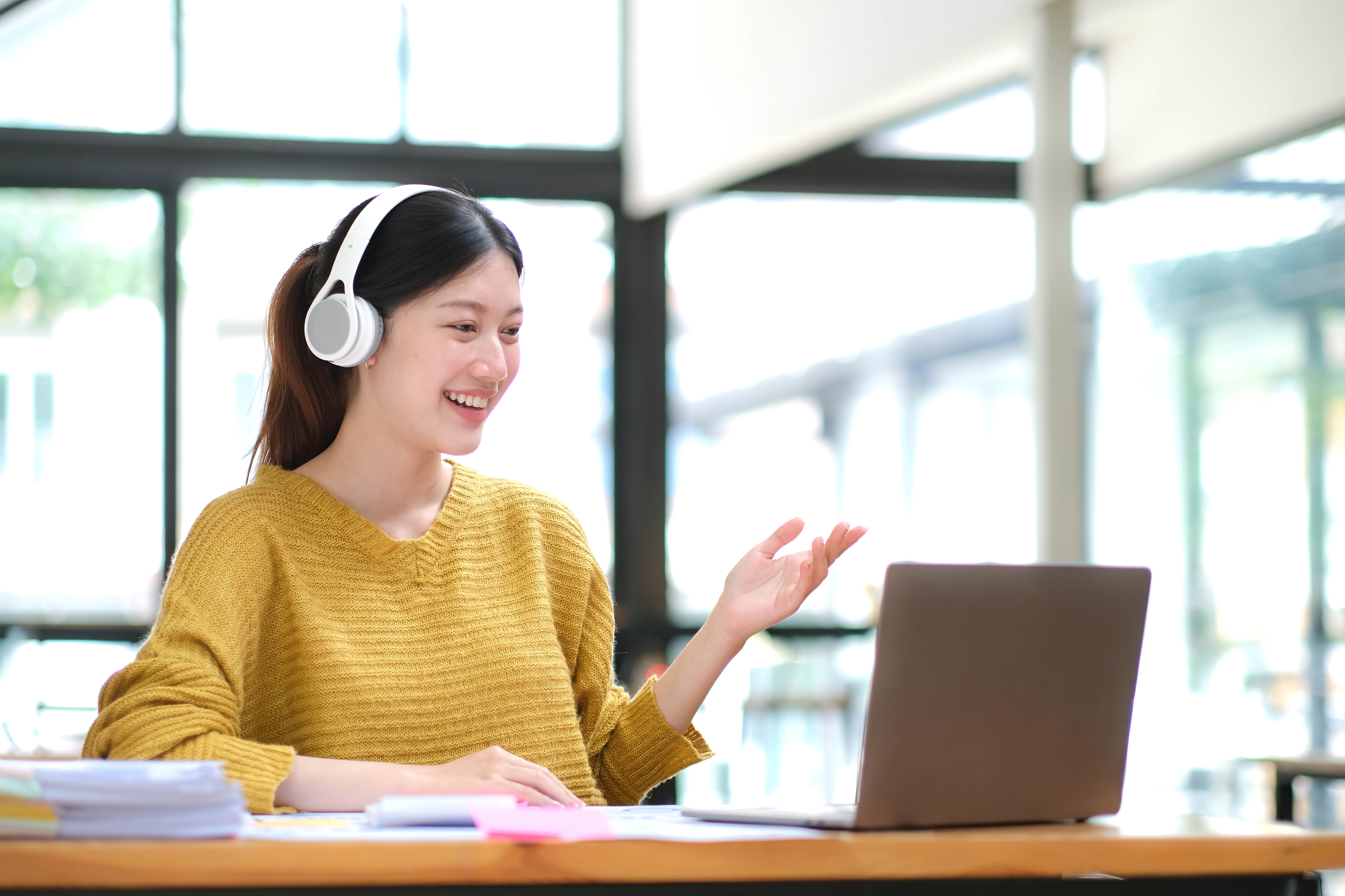 Asian woman with headphones interacting with laptop online learning