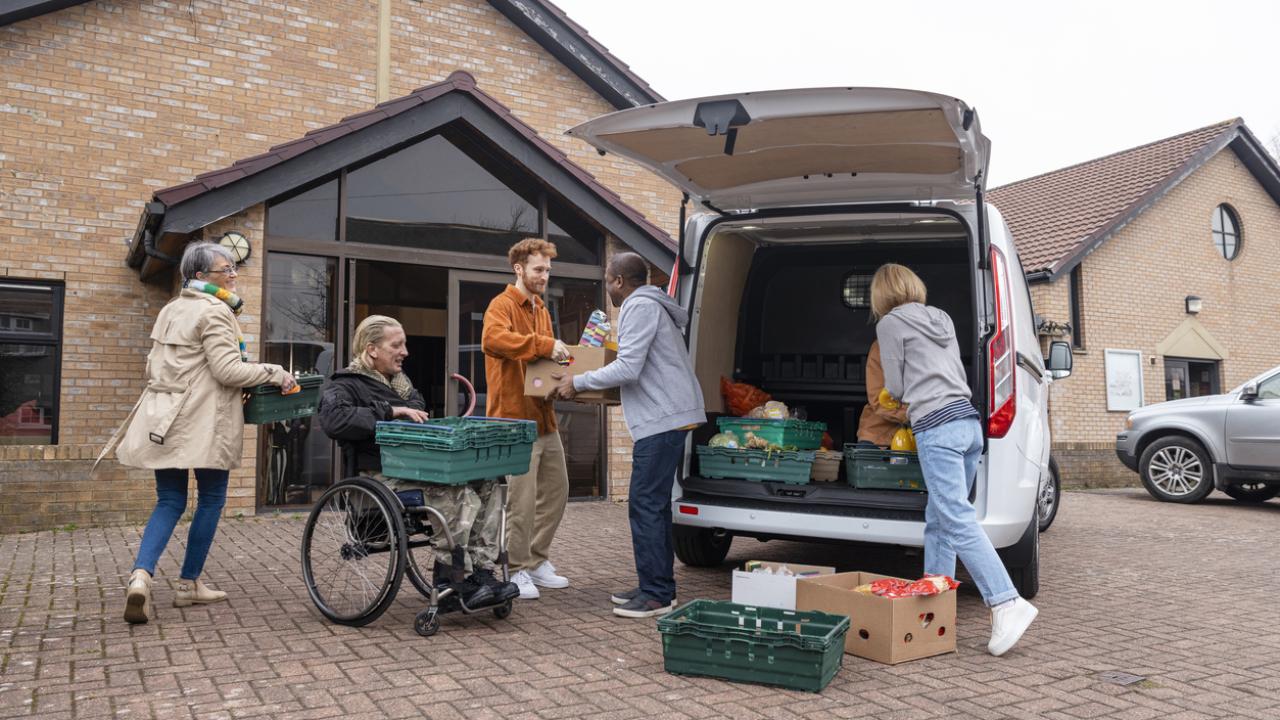 A group of people load charitable donations into the back of a van.