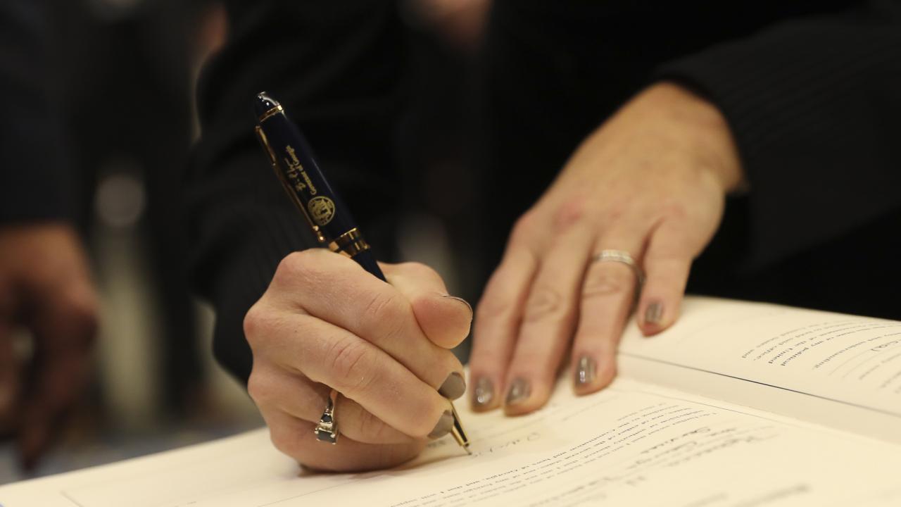 Image of DOAS Commissioner Rebecca Sullivan's hands, signing a document.