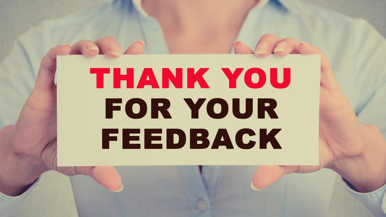 A pair of hands holds a sign that reads, &quot;THANK YOU FOR YOUR FEEDBACK.&quot;