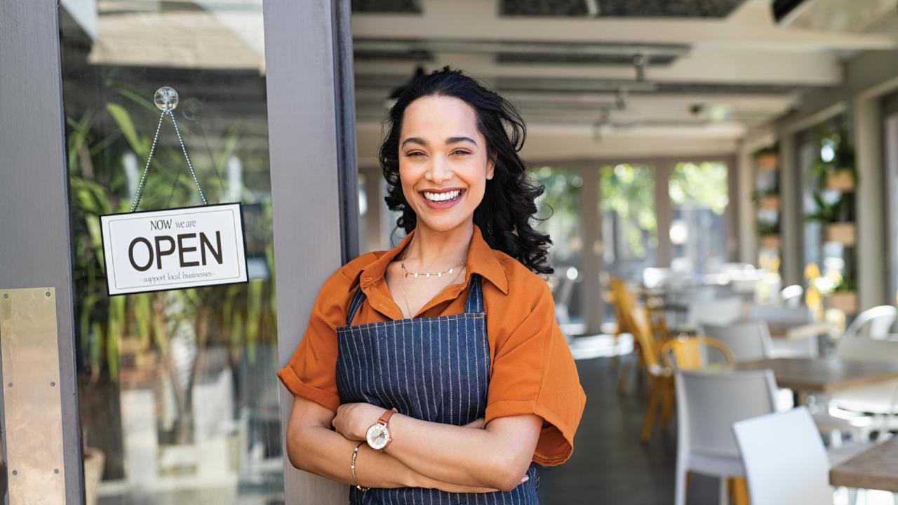 Image of a woman standing in front of her small business. 