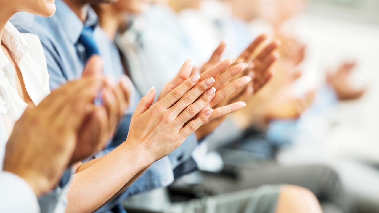 Individuals in a row clapping, image is focused on their hands.