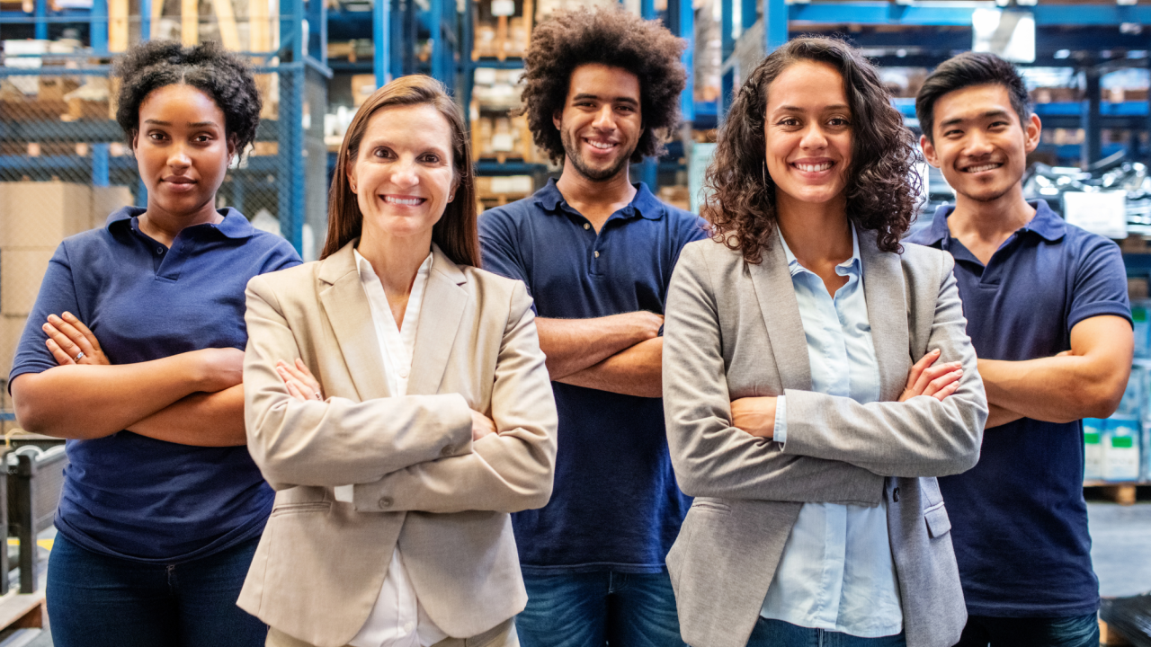 A group of five people stand in a warehouse, looking happy.