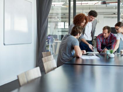 A group of people huddle at the end of a conference table.