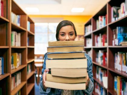 A woman in a library holds a stack of surplus books.