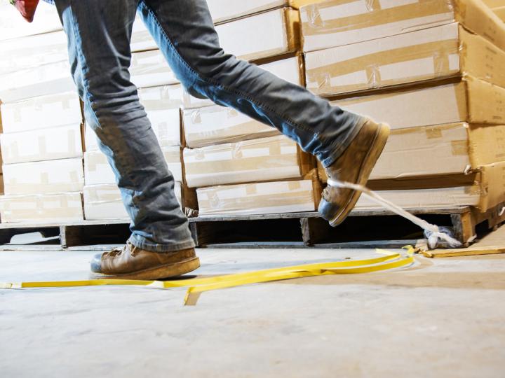 Image of a man tripping on tape in a warehouse. 