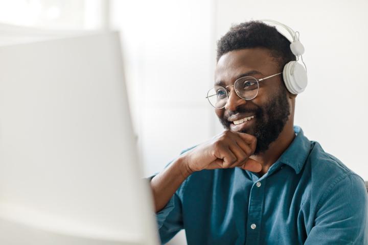 African American man with headphones smiling online learning
