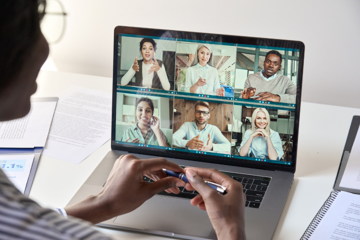 A person is viewing a laptop and participating in a virtual meeting.