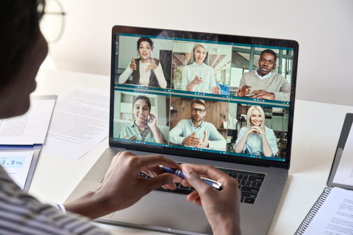 A person is viewing a laptop and participating in a virtual meeting. 