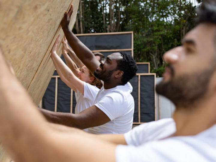 Image of volunteers raising a wall at a home-building site.
