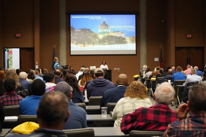 Photo depicts individuals at Fleet Day 2025 listening to the speaker. Photo is shot from the back of the room and shows a vast number of attendee&#039;s 