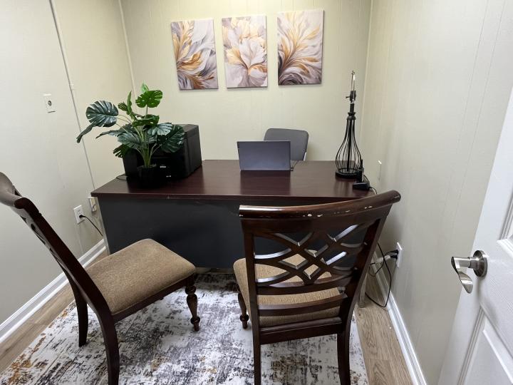 Pictures shows office desk with chairs in small office. 