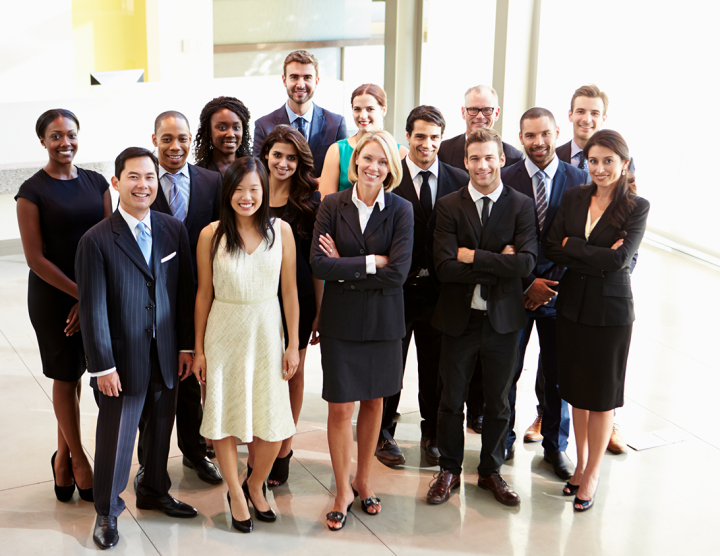 A smiling group of people dressed in work attire.
