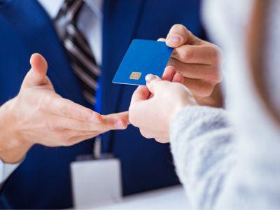 Closeup of a person in a suit accepting a payment card from another person.