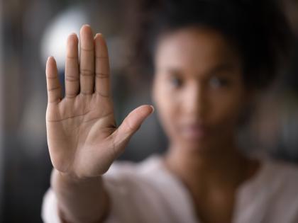 A woman, her face blurred, holds up her hand to forestall an unwelcome advance.