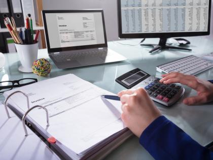 At a busy desk, a pair of hands hover over a set of contract requirements.