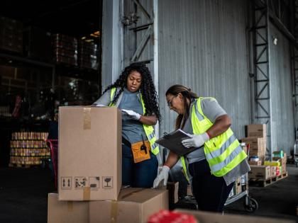 Two workers exam a delivery of returned items. 